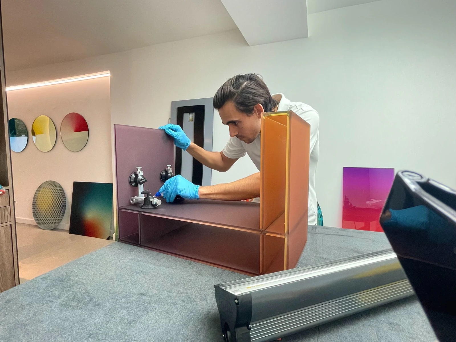 Guillermo Pernia montando un mueble de vidrio de color en el atelier de Glass Lab, con ventosas y guantes de nitrilo